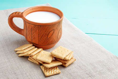 healthy breakfast cup of milk and crackers on a wooden blue surface, on linen napkin, close up, top vew の写真素材