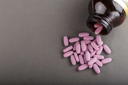 large pink tablets scattered on a black background, space for text