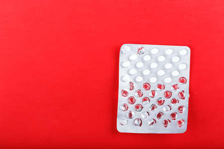started blister with pills on red background, medical treatment