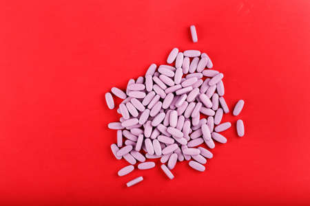 large pink tablets scattered on a red background, space for textの写真素材