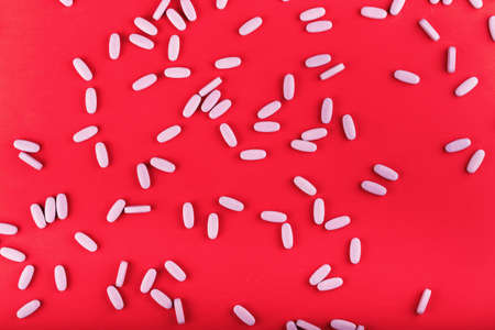 a lot of large pink tablets are scattered on a red background