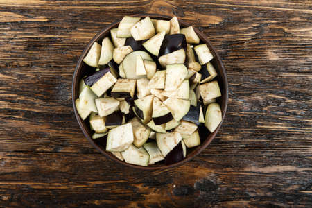 Diced eggplants in a clay plate on a wooden background. Horizontal photoの写真素材