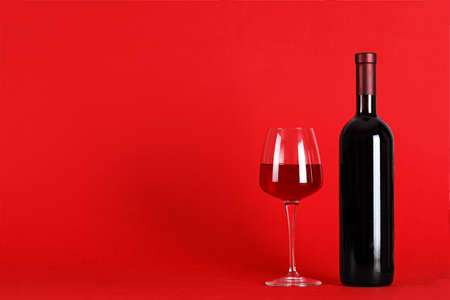 Wine set on a red background - Bottle of wine with a filled glass on a red background, space for textの写真素材