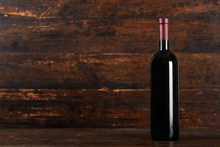 Closed bottle of red wine on a wooden background, space for textの写真素材