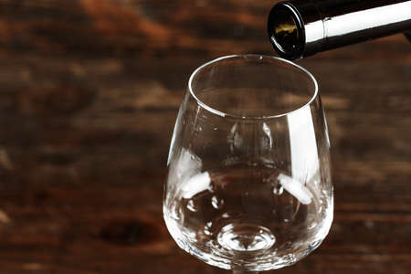 Red wine pour into a glass on a wooden background, space for textの写真素材