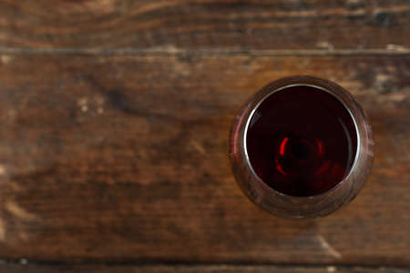 Red wine in a glass on a wooden background, top view, space for textの写真素材
