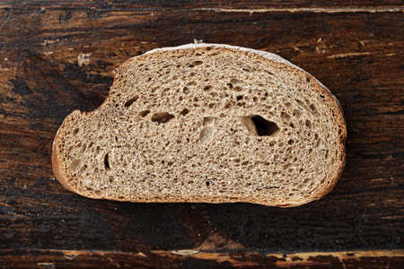 a slice of rye bread on a rough dark brown backgroundの写真素材