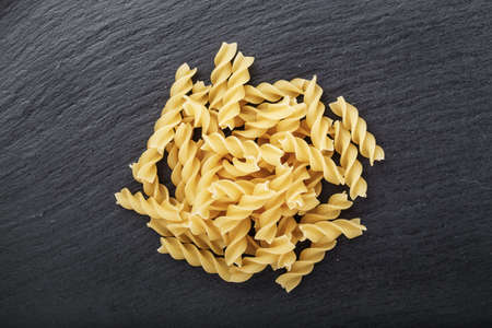 A portion of Rotini corkscrew pasta  on black stone table, top viewの写真素材