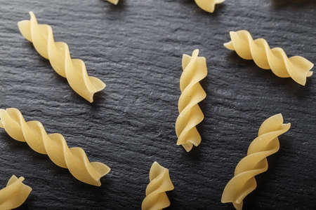 scattered of Rotini corkscrew pasta  on black stone table, top view. italian cultureの写真素材