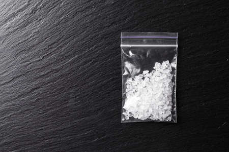 drugs in the form of crystals on a black background, methamphetamine in a plastic bagの写真素材