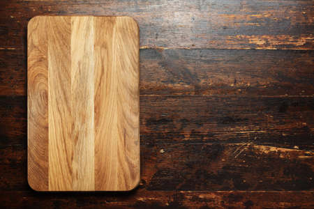 a new cutting board on a wooden background, top view, space for textの写真素材