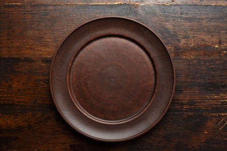 empty flat clay plate on a brown wooden background, top view, space for text
の写真素材