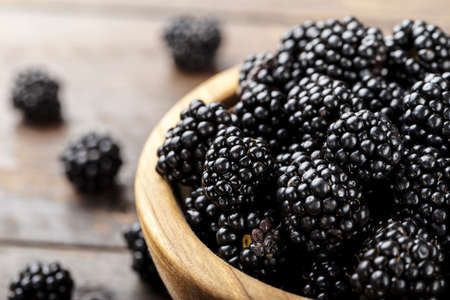Blackberry in a wooden plate on a wooden backgroundの写真素材