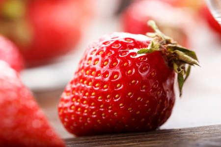 A ripe strawberry is scattered on a dark brown wooden background, space for textの写真素材