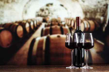 a glass and a bottle of wine on the background of barrels in the cellar
の写真素材