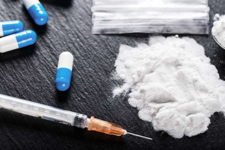 drugs in the form of a white powder on a black background, next is a syringe
の写真素材