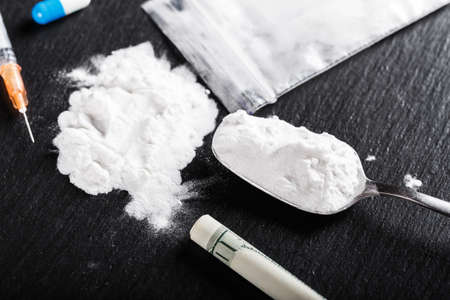 drugs in the form of a white powder on a black background, next is a syringe
の写真素材