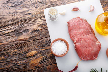 Raw steak with spices. Next to it is a red hot pepper, colorful pepper, olive oil.space for textの写真素材