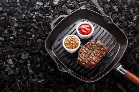 cooked steak on the grill pan on the steak is herb thyme, there are a number sauces - ketchup and...