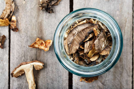 Dried mushrooms in a jar, sliced dried boletus on a wooden background