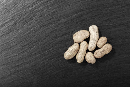 peanuts on black background, top view, space for text