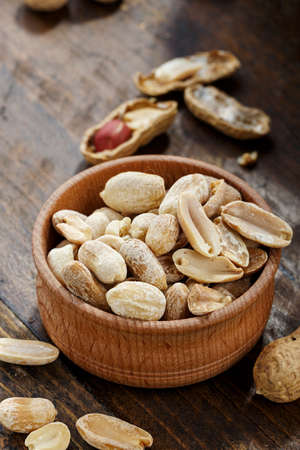 peanuts in a wooden plate on the table, a snack for beer