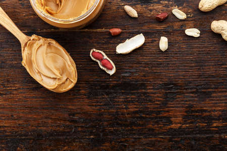 raw peanuts in a peel on a wooden background, space for text. spoon with peanut butter
の写真素材