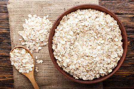 Oatmeal or oat flakes on dark wooden table