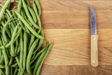 Green french beans on cutting board and dark wooden background, top viewの写真素材