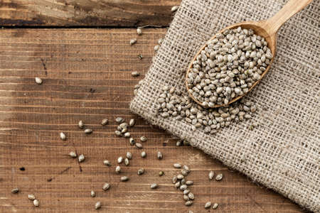 hemp seeds in a rustic wooden spoon on the burlap napkin, space for textの写真素材