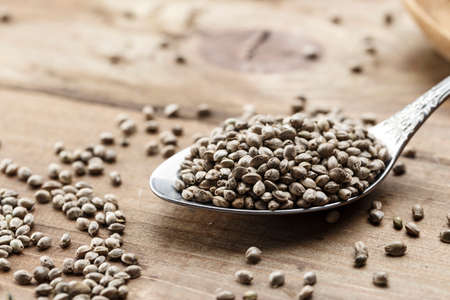 hemp seeds in a metal spoon on a wooden background, close-upの写真素材