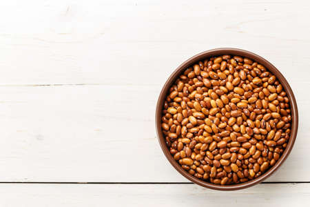 brown beans in a plate on a wooden background, top view, space for textの写真素材
