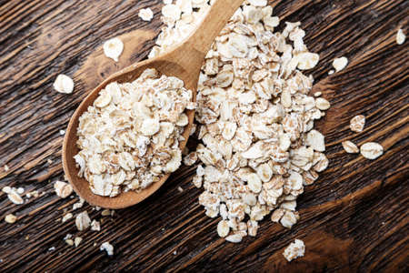 raw oat flakes in a spoon on a napkin from a sacking on a wooden table