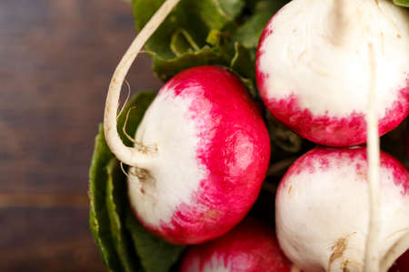 a bunch of washed radishes on a wooden background, space for text