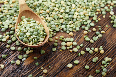 scattered dry green peas in a wooden spoon