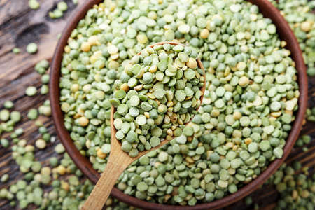 scattered dry green peas in a wooden spoonの写真素材
