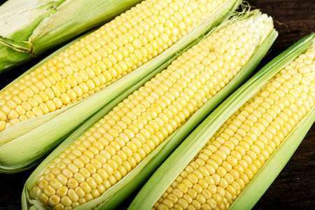 Fresh corn on cobs on wooden table, closeup