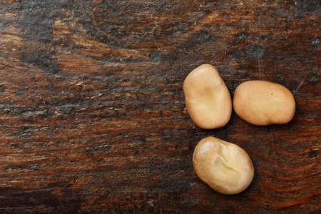 raw dry beans are scattered on a wooden background, space for text