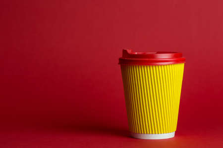 coffee to go in a disposable cup on a red background, place for text