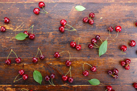 ripe sweet cherries are scattered on a wooden background, space for textの写真素材