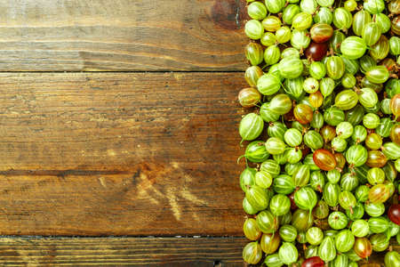 Gooseberries scattered on a wooden background, top view, space for textの写真素材