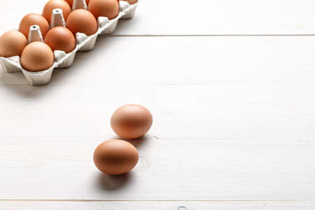 red chicken eggs in different shades on a white wooden backgroundの写真素材