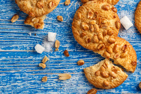 tasty cookies with peanuts on a blue shabby wooden background, biscuits broken.の写真素材
