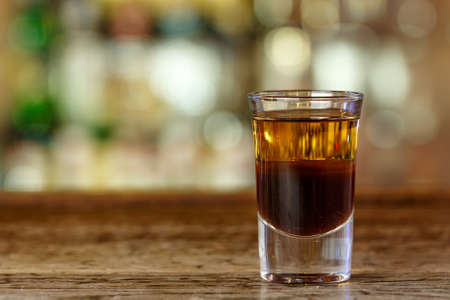 A strong cocktail in a nightclub stands on the bar on a blurry bottle background, space for text designの写真素材