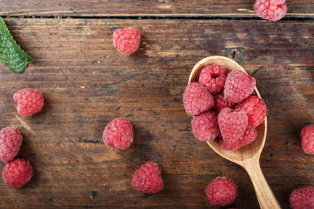 raw fresh raspberries in a spoon on a wooden background, well visible texture of berries, space for textの写真素材