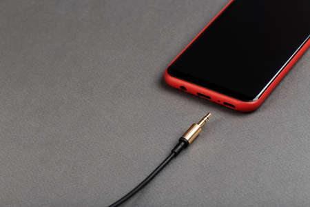 audio cable mini jack and mobile phone on a gray backgroundの写真素材