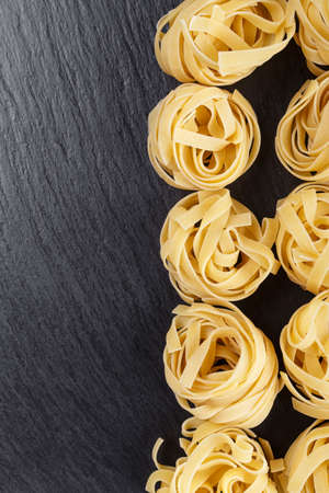 raw spaghetti nest. Italian pasta tagliatelle on slate. traditional italian cuisine
の写真素材