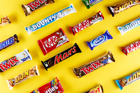 Kiev, Ukraine, March 29, 2018. different chocolate bars of modern companies. Chocolates lie in rows on a yellow background. Skittles - sweets, which are made by the company Vrigley. The rest of the chocolate is produced by Mars and Nestleのeditorial素材