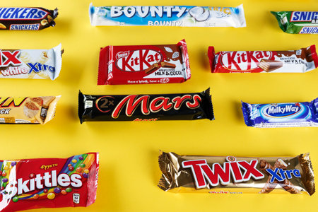 Kiev, Ukraine, March 29, 2018. different chocolate bars of modern companies. Chocolates lie in rows on a yellow background. Skittles - sweets, which are made by the company Vrigley. The rest of the chocolate is produced by Mars and Nestleのeditorial素材