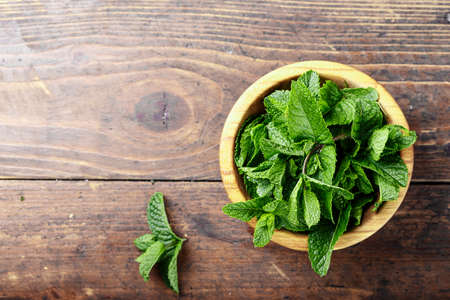 Fresh mint in a plate on a wooden background, space for textの写真素材